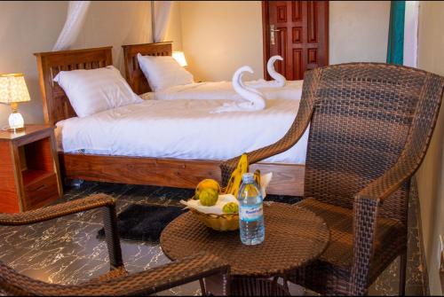 een slaapkamer met een bed en een tafel met een stoel bij CAR-NET HOTEL in Kisoro