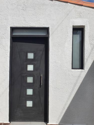 eine schwarze Tür in einem weißen Gebäude mit zwei Fenstern in der Unterkunft Aptoestudio full equipado y excelente ubicación in Cúcuta