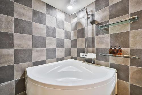 a bathroom with a toilet and a tiled wall at Hotel Yeogiuhtte Gumi Indong 2 in Gumi