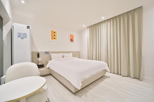 a white bedroom with a bed and a chair at Hotel Yeogiuhtte Gumi Indong 2 in Gumi