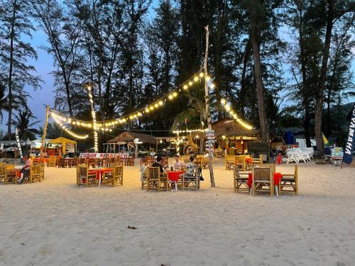 a group of tables and chairs on a beach with lights at Bangtao Rooms in Bang Tao Beach