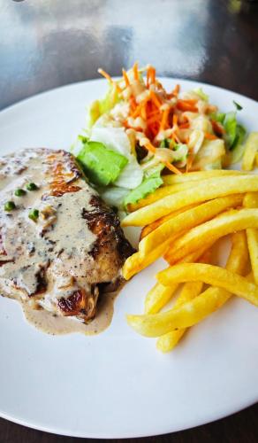 a white plate of food with french fries and meat at Bangtao Rooms in Bang Tao Beach