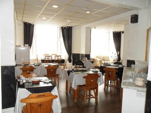 a dining room with tables and chairs and windows at Anzy Panzy Hotel and Apartments in Blackpool