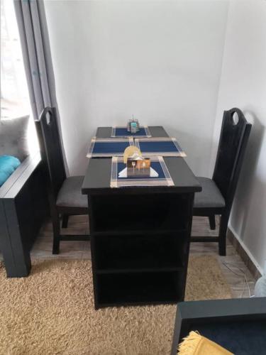 a black desk with two chairs in a room at Rozy homes Jinja in Jinja