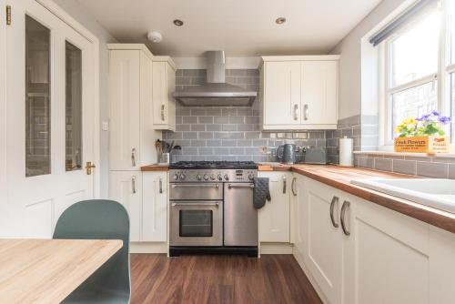 a kitchen with white cabinets and a stove and a sink at Cosy Roseburn Apartment, Edinburgh - 2 Bedrooms, FREE PARKING in Edinburgh