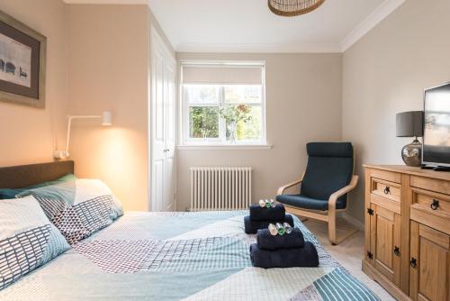 Un dormitorio con una cama y una silla y un televisor. en Cosy Roseburn Apartment, Edinburgh - 2 Bedrooms, FREE PARKING, en Edimburgo