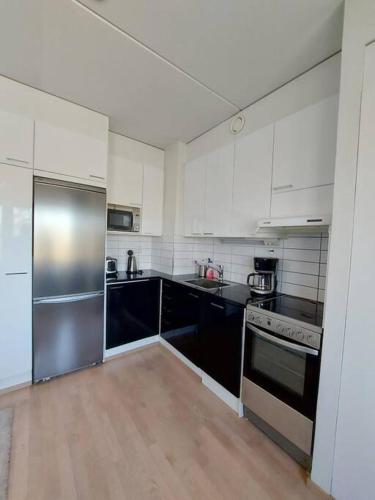 a kitchen with stainless steel appliances and black cabinets at Kotimaailma - Valoisa kalustettu yksiö Espoossa in Espoo