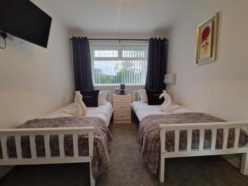 two twin beds in a room with a window at Lakeside 3 Bedroom Bungalow Retreat Merthyr Tydfil in Cefn-coed-y-cymmer