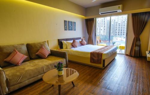 a hotel room with a bed and a couch at Studio Flat Near Airport in Surat