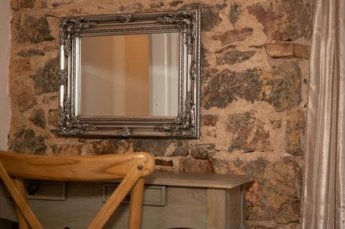 a mirror on a stone wall with a wooden chair at Quirky Boutique 1840s Stable in Torquay