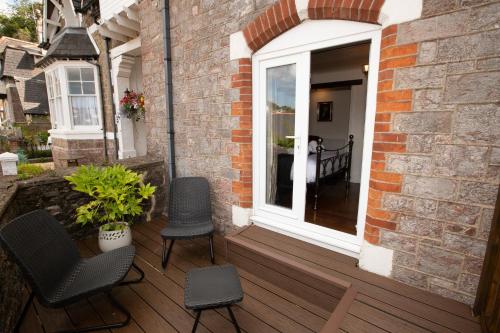 a porch with two chairs and a window on a house at Quirky Boutique 1840s Stable in Torquay