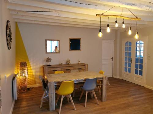 ein Esszimmer mit einem Holztisch und Stühlen in der Unterkunft Maison Chaleureuse dans petite cité de caractère in Fresnay-sur-Sarthe