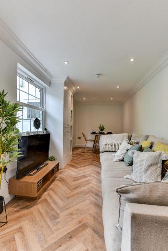 a living room with a couch and a television at Spacious Brighton Home 2 Ensuites, Weekly & Monthly Stays-Marine LGF by Bluehouse Shortlets Brighton in Brighton & Hove