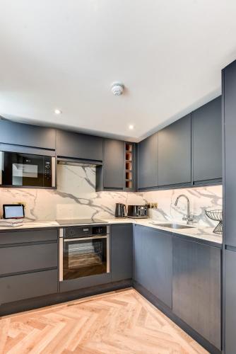 a kitchen with gray cabinets and stainless steel appliances at Spacious Brighton Home 2 Ensuites, Weekly & Monthly Stays-Marine LGF by Bluehouse Shortlets Brighton in Brighton & Hove