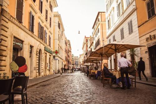 a cobblestone street with people sitting at tables in an alley at 450mt to Basilica S.Pietro in Rome