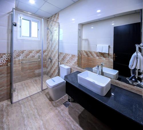 La salle de bains est pourvue d'un lavabo, de toilettes et d'une douche. dans l'établissement Amber Tower, à Al Ghurayfah