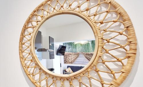 un miroir avec un cadre en rotin sur un mur dans l'établissement Le Ptit Paradis - Calme - Wifi - Cour privée - Relax BNB, à Mulhouse