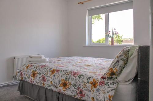 um quarto com uma cama com um cobertor florido e uma janela em 2 BEDROOM The White House em Cahersiveen