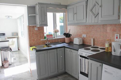 a kitchen with white cabinets and a stove top oven at 2 BEDROOM The White House in Cahersiveen