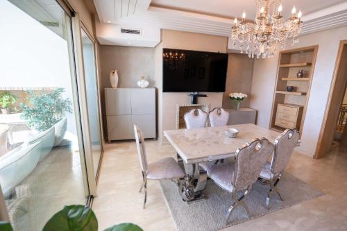 a dining room with a table and chairs and a chandelier at Appartement bord de mer +piscine in Tangier