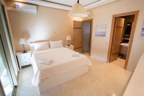 a bedroom with a large white bed and a bathroom at Appartement bord de mer +piscine in Tangier