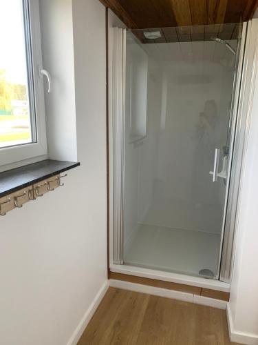 eine Glasdusche in einem Zimmer mit Fenster in der Unterkunft Dunenestje in Oostduinkerke