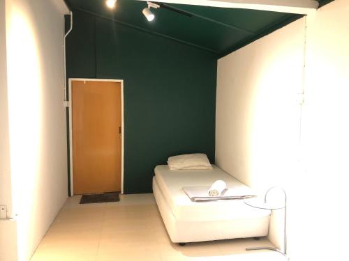 a small room with a bed and a green wall at Rumah Tepi Istana in Kuala Terengganu