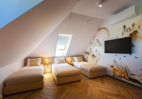 a attic room with two beds and a flat screen tv at Lisie Sprawki in Bebło