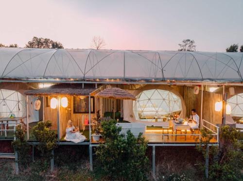 a house with people sitting at tables in front of it at Paopao Orange Farm and Home stay in Mae Rim