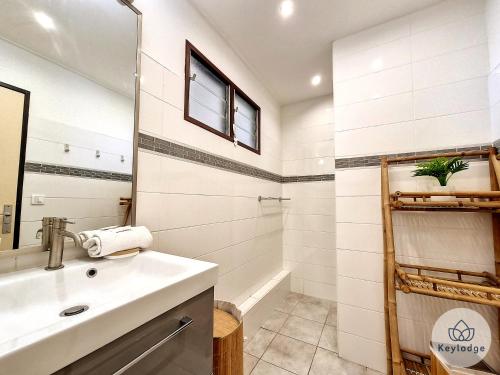 een witte badkamer met een wastafel en een spiegel bij Bulle des Roches Noires - 5min de la Plage des Roches Noires - T2 bis - 50m² in Saint-Paul