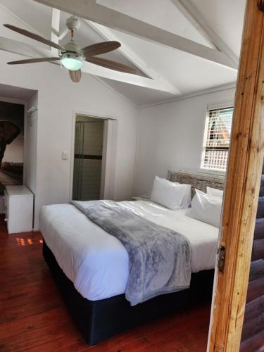 a bedroom with a large bed with a ceiling fan at FM GUEST LODGE Comfort, Tranquility & Peace of Mind in Johannesburg