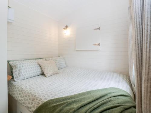 een klein bed in een kamer met witte muren bij Hazel in Cirencester