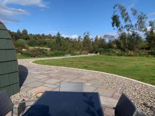 a table and chairs on a patio with a lawn at Tawny Owl Pod with Hot Tub in Oban