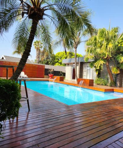 a swimming pool with a palm tree on a deck at FM GUEST LODGE Comfort, Tranquility & Peace of Mind in Johannesburg