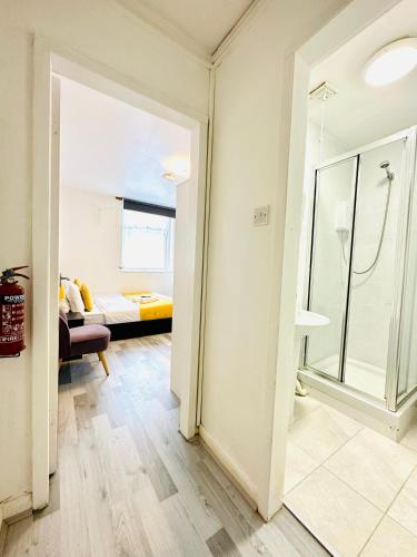 a bathroom with a glass shower and a living room at Private Studio Flat in City 1160 in London