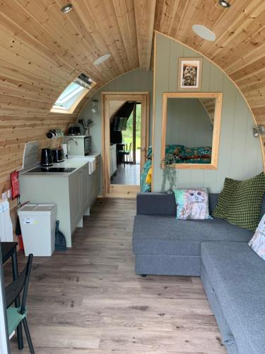 a living room with a couch and a kitchen at Tawny Owl Pod with Hot Tub in Oban