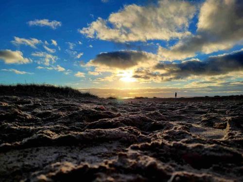 a sunset on a sandy beach with the sun setting at KvarteretSkatan! in Ystad