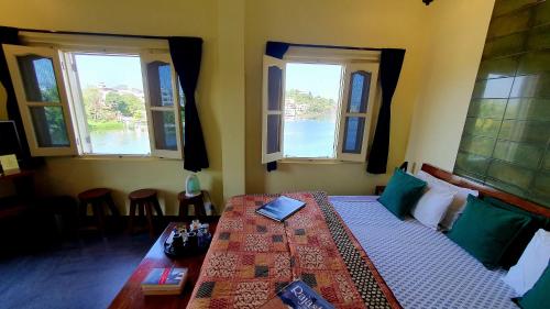a bedroom with a bed with windows and a table at Oolala - Your lake house in the center of Udaipur in Udaipur