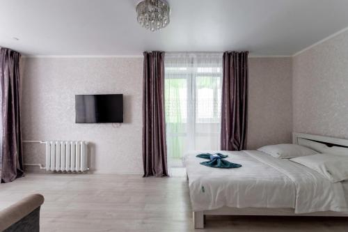 1 dormitorio con 1 cama y TV en la pared en Альпина en Petropavlovsk