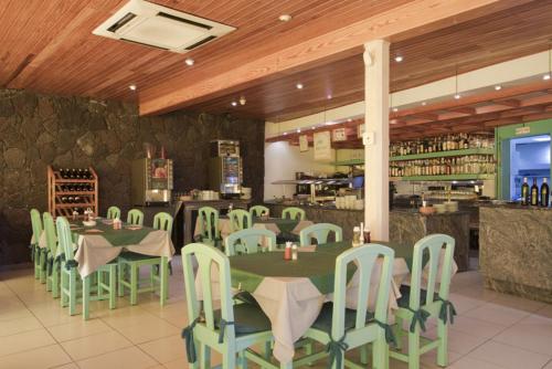 a restaurant with green tables and chairs and a bar at Apartamentos Arena Dorada in Puerto del Carmen