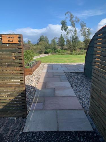 a walkway with a sign on a brick wall at Tawny Owl Pod with Hot Tub in Oban