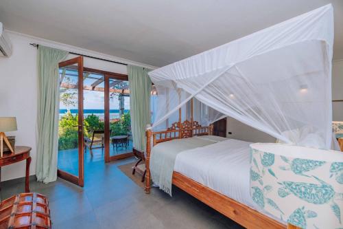 a bedroom with a bed and a view of the ocean at Karabai Villa in Matemwe