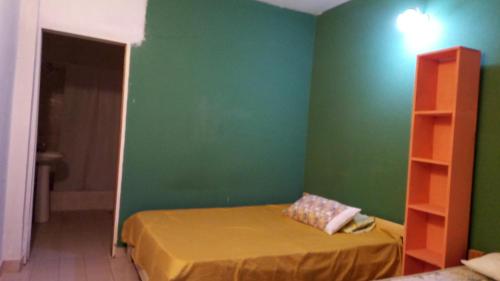 een slaapkamer met een groene muur en een bed bij Casa planta baja en Faro Mogotes in Mar del Plata
