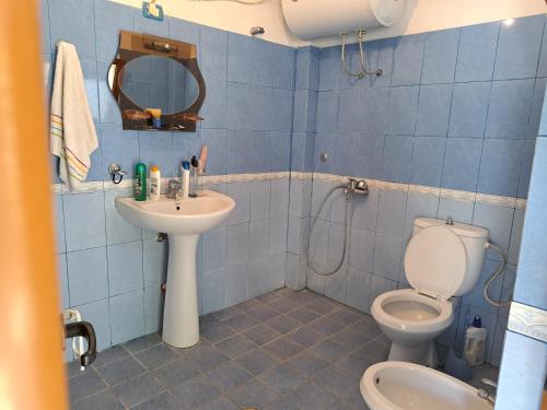 a blue tiled bathroom with a toilet and a sink at Denis's House in Gramsh