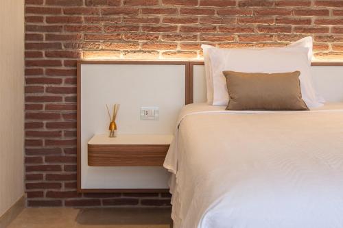 a bedroom with a bed and a brick wall at Hotel Tango Suítes Cumbuco in Cumbuco