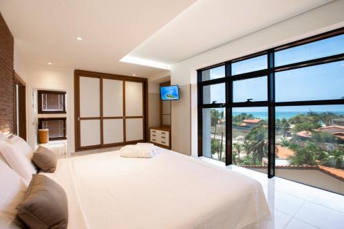 a bedroom with a white bed and a large window at Hotel Tango Suítes Cumbuco in Cumbuco