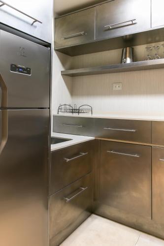 a kitchen with a stainless steel refrigerator and cabinets at Hotel Tango Suítes Cumbuco in Cumbuco