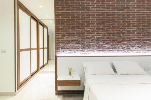 a bedroom with a brick wall and a bed at Hotel Tango Suítes Cumbuco in Cumbuco