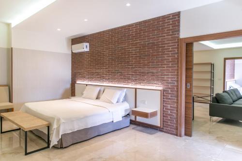 a bedroom with a bed and a brick wall at Hotel Tango Suítes Cumbuco in Cumbuco