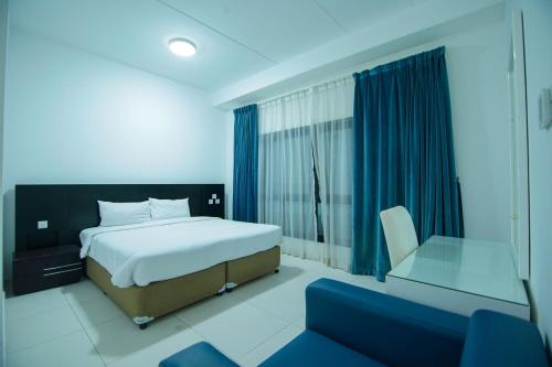 a bedroom with a bed and a chair and a window at Home Away Holiday Homes in Dubai